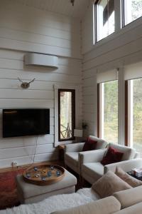 a living room with white furniture and a flat screen tv at Jaloilevi - Kätkänrinne in Kittilä