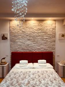 a bedroom with a red headboard and a brick wall at Serendipity in Bentivoglio