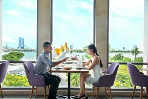 un hombre y una mujer sentados en una mesa con copas de vino en Vanda Hotel, en Da Nang