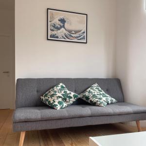 ein graues Sofa mit zwei Kissen im Wohnzimmer in der Unterkunft Les Fleurettes in De Panne