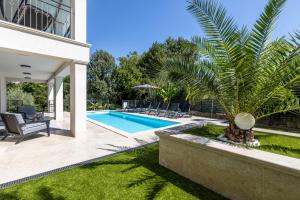 a swimming pool with a palm tree in a yard at Villa Pafran with heated pool Krk in Krk
