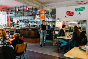 a man standing in a restaurant with people sitting at tables at Hotel Credible in Nijmegen