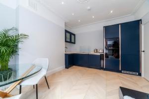 a kitchen with a glass table and blue cabinets at Bright King's Cross 2 bedroom flat with patio in London