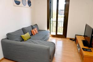 Sala de estar con sofá gris y TV en Homenfun Barcelona Plaza España, en Barcelona