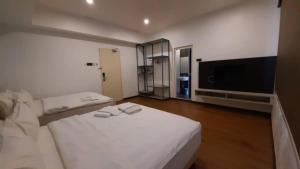 a bedroom with two beds and a flat screen tv at TT Dorf Hotel Taiping in Taiping
