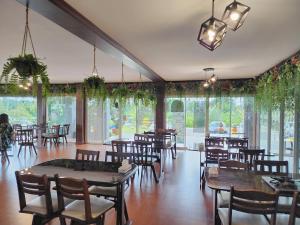 a dining room with tables and chairs and windows at Tara Spa Ratchaburi in Ban Bang Kra