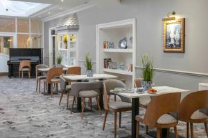 uma sala de jantar com mesas e cadeiras e um piano em The Craiglands Hotel Sure Hotel Collection by Best Western em Ilkley