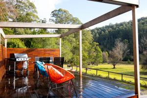 a deck with a grill and a table and chairs at Toorongo River Chalets in Noojee