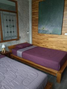 two beds in a bedroom with purple sheets at ป้าเฒ่าเฝ้าสวน in Lampang