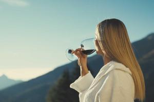 Una donna che beve un bicchiere di vino in montagna di Wohnung Kreuzjoch 142- Naviser Huette a Navis