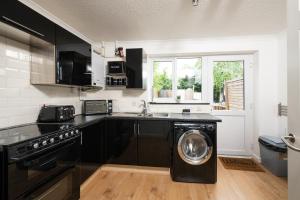 a kitchen with black cabinets and a washing machine at Free Parking Good location With Garden in Taunton