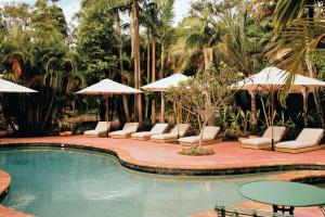 a swimming pool with lounge chairs and umbrellas at The Sunseeker, Byron Bay in Byron Bay