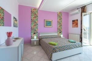 um quarto com paredes cor-de-rosa e roxo e uma cama em A Casa Mia em Floridia
