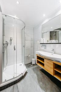 biała łazienka z prysznicem i umywalką w obiekcie Hotel Taxerhof w mieście Radstadt