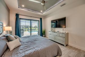 um quarto com uma cama grande e uma televisão em Villa Mangifera with Salt Water Pool & Spa, EV-Loading em Cape Coral