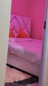 ein rosafarbenes Schlafzimmer mit einem Bett mit roten Kissen in der Unterkunft Shamir trm studio in Nairobi