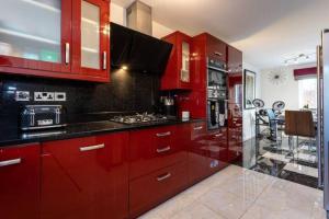une cuisine avec des placards rouges et un comptoir dans l'établissement Beautifully designed 3 Bed House - in Manchester, à Manchester