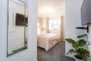 Beautifully designed 3 Bed House - in Manchester في مانشستر: صورتين لغرفة نوم مع سرير ومرآة