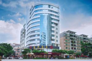 a tall glass building with a sign in front of it at Foshan Guanxin Hotel in Shunde