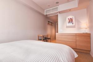a bedroom with a white bed and a dresser at KABIN Koji in Kyoto