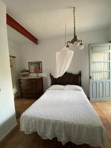 1 dormitorio con cama blanca y lámpara de araña en Finca La Jaquima, en Avileses
