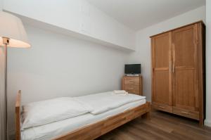 ハンブルクにあるAppartements in der historischen Deichstrasse contactless Check inのベッドルーム1室(ベッド1台付)、木製キャビネットが備わります。