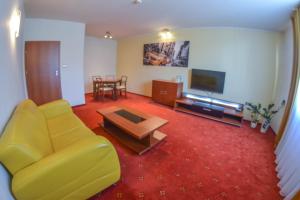 a living room with a yellow couch and a tv at Hotel Neo in Tarnowskie Góry
