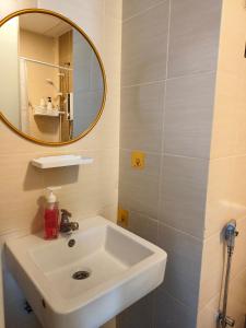 a bathroom with a white sink and a mirror at Pleasant Amenities ITCC Manhattan Suites in Penampang