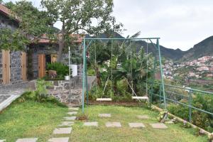 a garden in front of a house with a swing at Vale dos Ilhéus in Machico