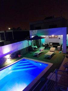 a swimming pool at night with chairs and lights at Valadares House in Corroios