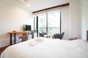 Bird Hostel في Shimmachidōri: غرفة نوم بسرير ابيض ومكتب مع كراسي