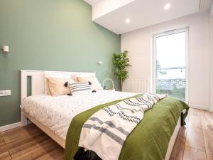 Un dormitorio con una cama con paredes verdes y una ventana en OAK TREE Apartment en Dąbrowa Górnicza