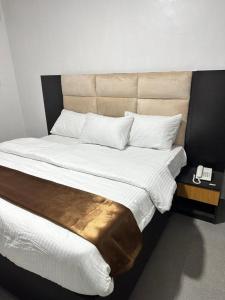 a bedroom with a large bed with a phone on it at Maxx Msquare Hotel in Agege