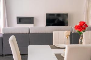a living room with a couch and a table with red roses at Luxurious Villa Marly II in Castelldefels