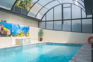 an indoor swimming pool with a large window and a large swimming pool at Luxurious Villa Marly II piscina climatizada in Castelldefels