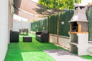 un patio al aire libre con césped verde y parrilla en Luxurious Villa Marly II, en Castelldefels