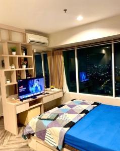 Schlafzimmer mit einem Bett und einem Schreibtisch mit einem Computer in der Unterkunft Apartment Grand Kamala Lagoon By Davalina Rooms in Pulosirih
