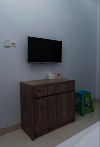 a flat screen tv on a wall with a wooden cabinet at OYO Life 92878 Kost Padma Syariah in Kandang-besar