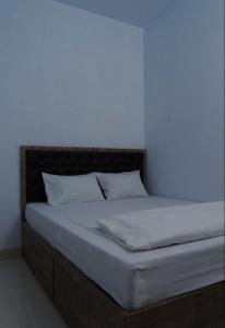 a bed with white sheets and pillows in a room at OYO Life 92878 Kost Padma Syariah in Kandang-besar