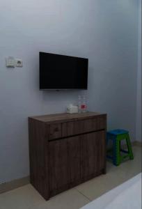 a flat screen tv on a wall with a wooden cabinet at OYO Life 92878 Kost Padma Syariah in Kandang-besar