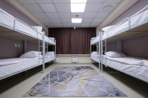 a room with three bunk beds and a rug at Mouse House Hostel in Almaty