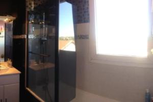 La salle de bains est pourvue d'une douche en verre et d'une fenêtre. dans l'établissement T2-42m2-Climatisation, lumière tamisée-garage, à Bourgoin-Jallieu