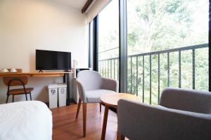 a room with a bed and a balcony with a television at Bird Hostel in Shimmachidōri