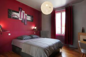 een rode slaapkamer met een bed en een rode muur bij L'Iliade - Chambres d'hôtes - B&B à Bouzy in Bouzy