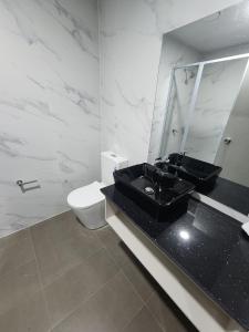 a bathroom with a black sink and a toilet at Vualiku Hotel & Apartments in Nadi