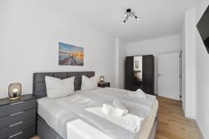ein Schlafzimmer mit einem großen weißen Bett mit weißer Bettwäsche in der Unterkunft Infinity Stay: Ferienappartments Rheinstrasse in Wilhelmshaven