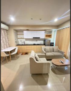 ein Wohnzimmer mit Sofas und einem Tisch sowie eine Küche in der Unterkunft Apartment Grand Kamala Lagoon By Davalina Rooms in Pulosirih