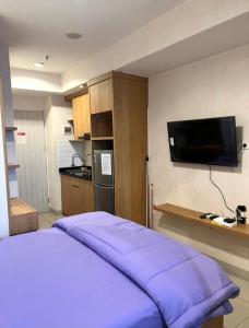 1 Schlafzimmer mit einem lila Bett und einem TV in der Unterkunft Apartment Grand Kamala Lagoon By Davalina Rooms in Pulosirih