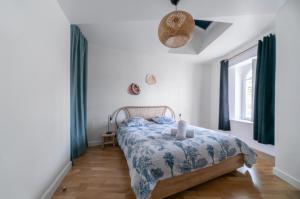 a bedroom with a bed with a blue and white comforter at Le Wilson - Appartement design - Hyper centre in Vichy