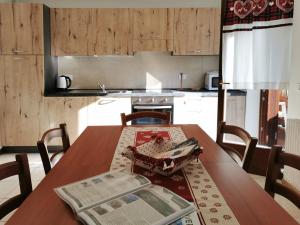 una cocina con una mesa de madera con un periódico. en Residence Ruina, en Pinzolo